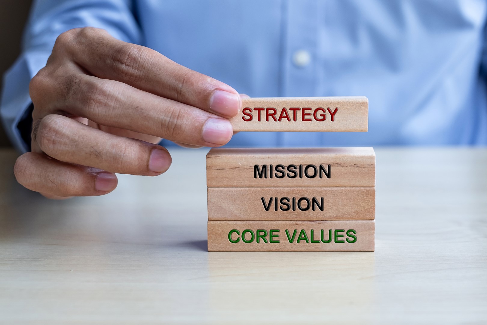 Businessman hand holding wooden building blocks on table background. Business planning, Risk Management, Solution and strategy Concepts